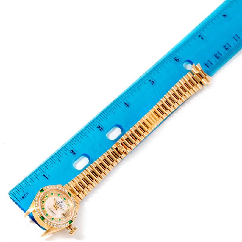 The image shows a Rolex President 79068 Women's Yellow Gold Mother of Pearl Dial 79068 Women's Yellow Gold Mother of Pearl Dial watch laid flat next to a blue ruler, showcasing the watch face and part of the bracelet.