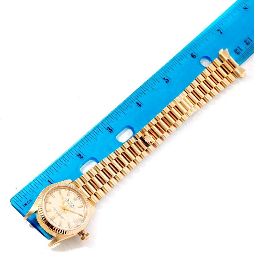 The image shows the Rolex President 68278 Women's Yellow Gold Beige Dial 68278 Women's Yellow Gold Beige Dial watch laid flat next to a blue ruler, displaying its face and band.