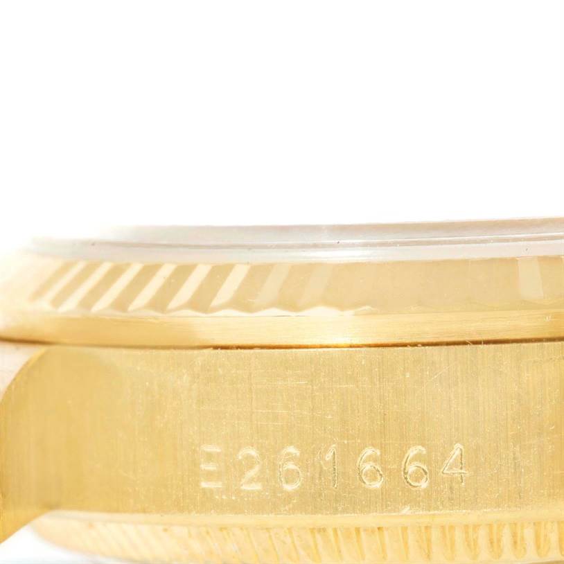 The image shows a side angle of the case of a Rolex President 68278 Women's Yellow Gold Beige Dial 68278 Women's Yellow Gold Beige Dial model watch, highlighting its engraving and fluted bezel.