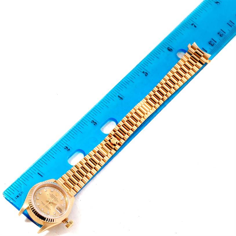 The image shows a Rolex President 69178 Women's Yellow Gold Champagne Dial 69178 Women's Yellow Gold Champagne Dial watch with a gold band, face, and bezel, placed next to a blue ruler for measurement.
