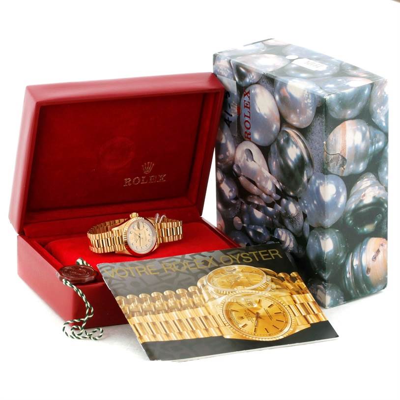 The image shows a Rolex President 69178 Women's Yellow Gold Champagne Dial 69178 Women's Yellow Gold Champagne Dial model watch inside a red box, with an outer decorative box and a brochure partially covering the watch.