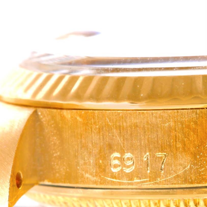 The image shows a close-up side view of the bezel and case of a Rolex President 6917 Women's Yellow Gold Brown Dial 6917 Women's Yellow Gold Brown Dial model watch with part of its serial number.