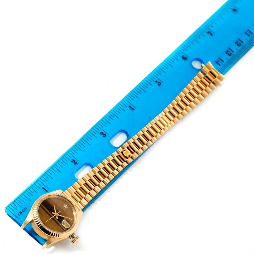 The image shows the Rolex President 6917 Women's Yellow Gold Brown Dial 6917 Women's Yellow Gold Brown Dial model watch from a top-down angle with its bracelet and case measured by a blue ruler.