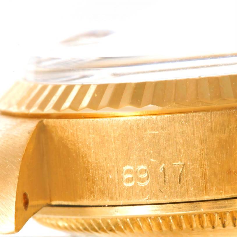 Close-up of the side of a Rolex President 6917 Women's Yellow Gold White Dial 6917 Women's Yellow Gold White Dial watch model, showing the gold casing and partial serial number.