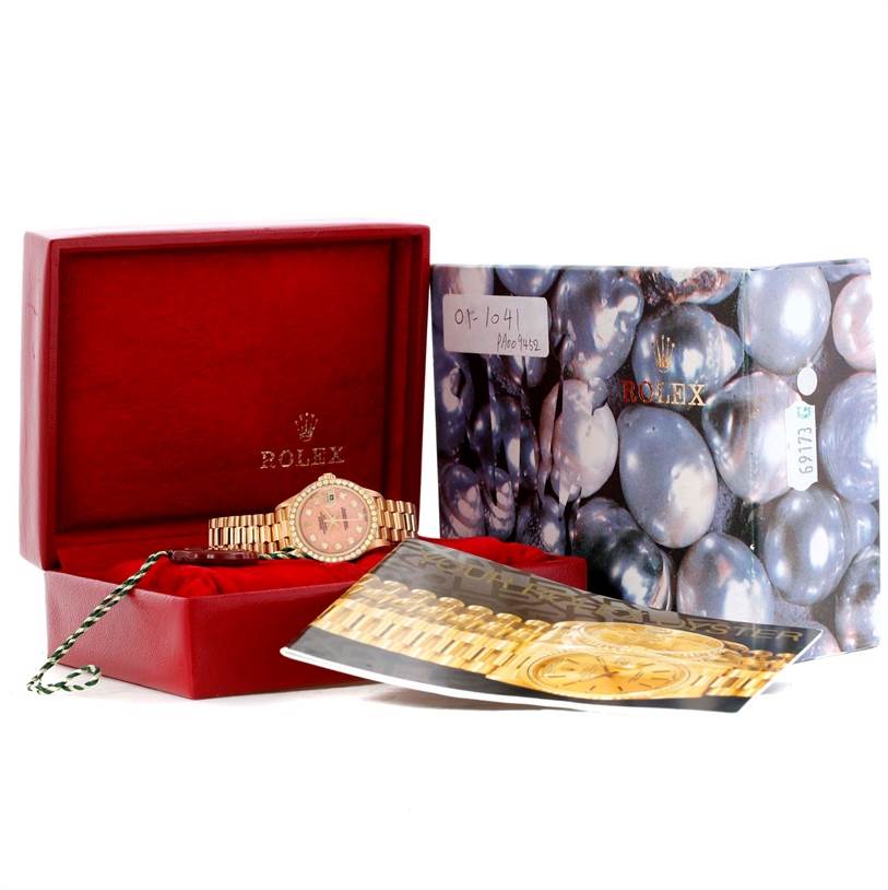 The image shows a Rolex President 69138 Women
s Yellow Gold Pink Dial 69138 Women
s Yellow Gold Pink Dial model watch in its box, with accompanying booklets and packaging materials.