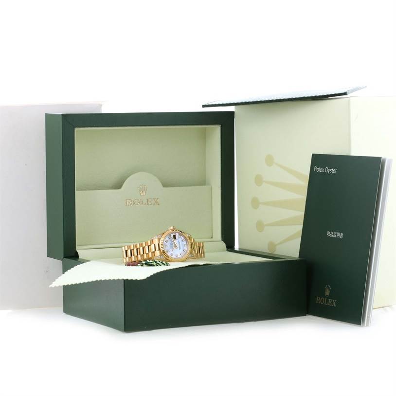 The image shows a Rolex President 179238 Women
s Yellow Gold Mother of Pearl Dial 179238 Women
s Yellow Gold Mother of Pearl Dial model watch in its open box, with its manual and additional outer packaging also visible.