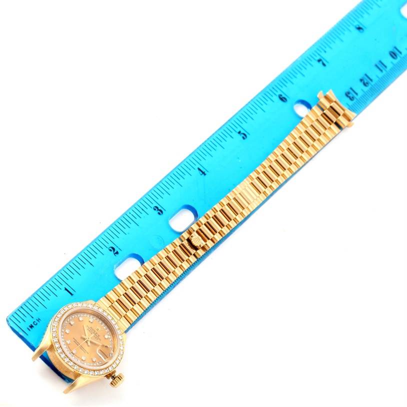 The image shows the Rolex President 69138 Women's Yellow Gold Champagne Dial 69138 Women's Yellow Gold Champagne Dial watch face and band, placed alongside a blue ruler for size reference.