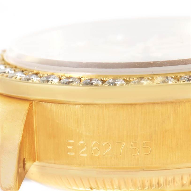 The image shows a close-up angle of the side of a Rolex President 69138 Women's Yellow Gold Champagne Dial 69138 Women's Yellow Gold Champagne Dial, highlighting the bezel with diamonds and part of the case with the serial number.
