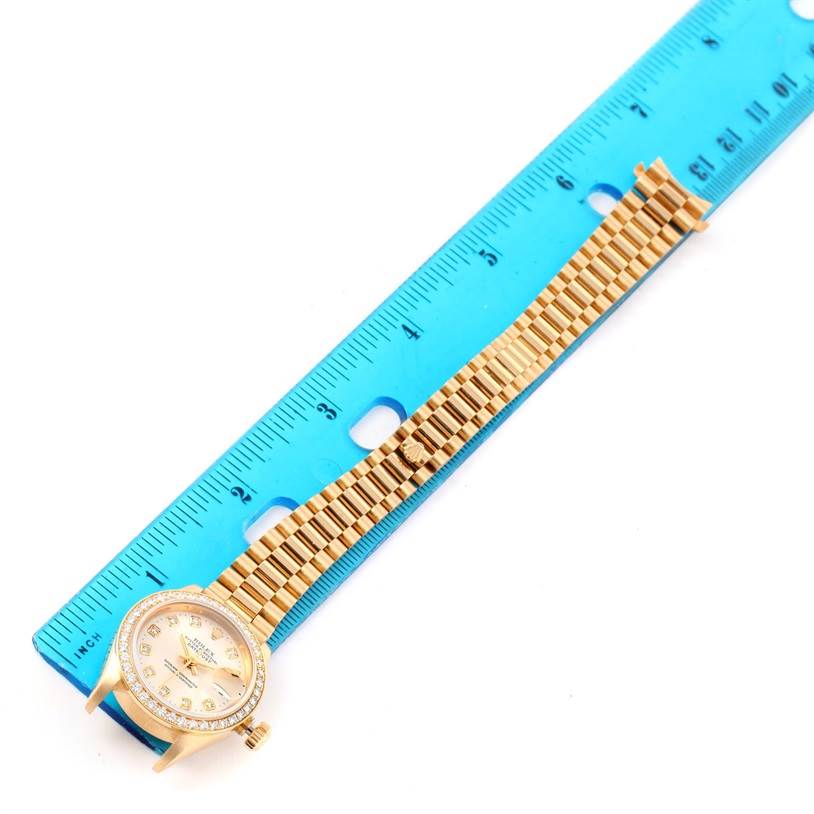 The image shows a Rolex President 79138 Women's Yellow Gold Silver Dial 79138 Women's Yellow Gold Silver Dial model watch, with the face and band aligned next to a blue ruler for scale.