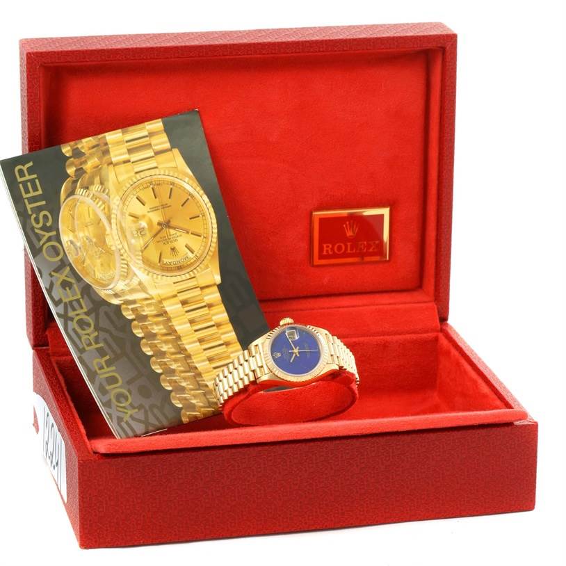 The Rolex President 69178 Women's Yellow Gold Blue Dial 69178 Women's Yellow Gold Blue Dial model watch is shown at an angle inside an open red box, alongside a brochure.
