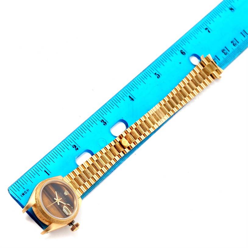 The Rolex President 69278 Women's Yellow Gold Brown Dial 69278 Women's Yellow Gold Brown Dial model watch is shown from a top-down angle, displaying its face and band alongside a blue ruler for scale.