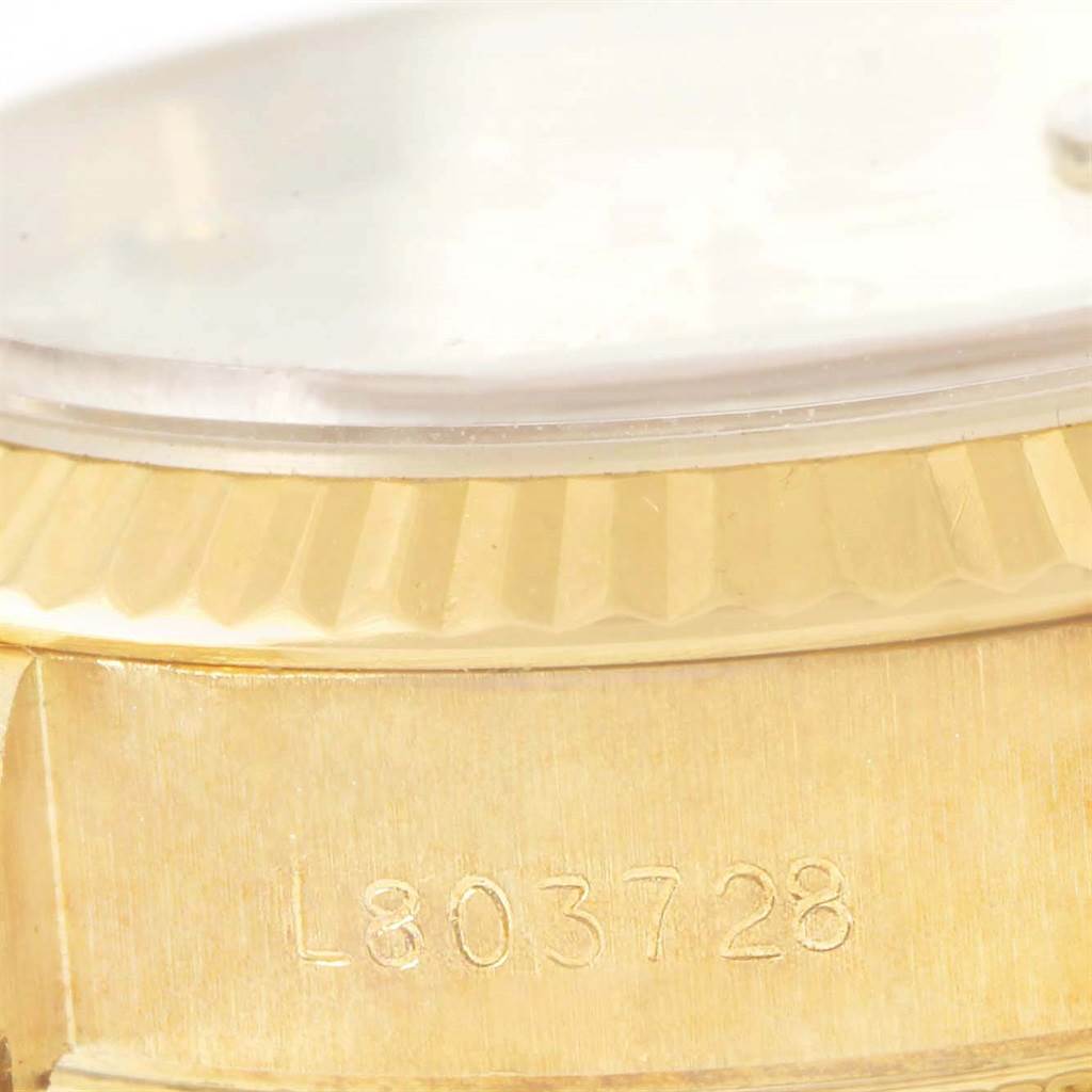 This close-up image of a Rolex President 69178 Women's Yellow Gold Beige Dial 69178 Women's Yellow Gold Beige Dial model watch shows part of the case, bezel, and the edge of the crystal, including the serial number.