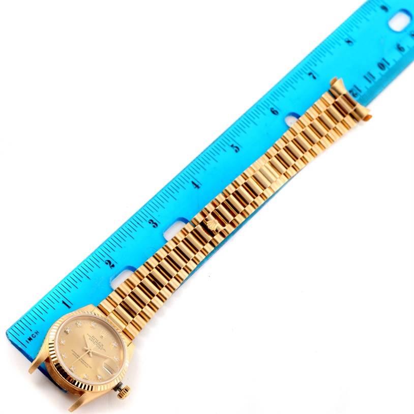 The image shows a Rolex President 68278 Women's Yellow Gold Champagne Dial 68278 Women's Yellow Gold Champagne Dial model watch laid flat alongside a blue measuring ruler.