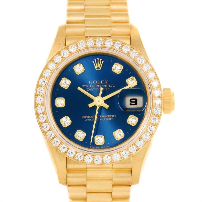 The image shows a front view of a Rolex President 69138 Women's Yellow Gold Blue Dial 69138 Women's Yellow Gold Blue Dial model watch featuring a diamond-encrusted bezel, gold bracelet, and blue dial.