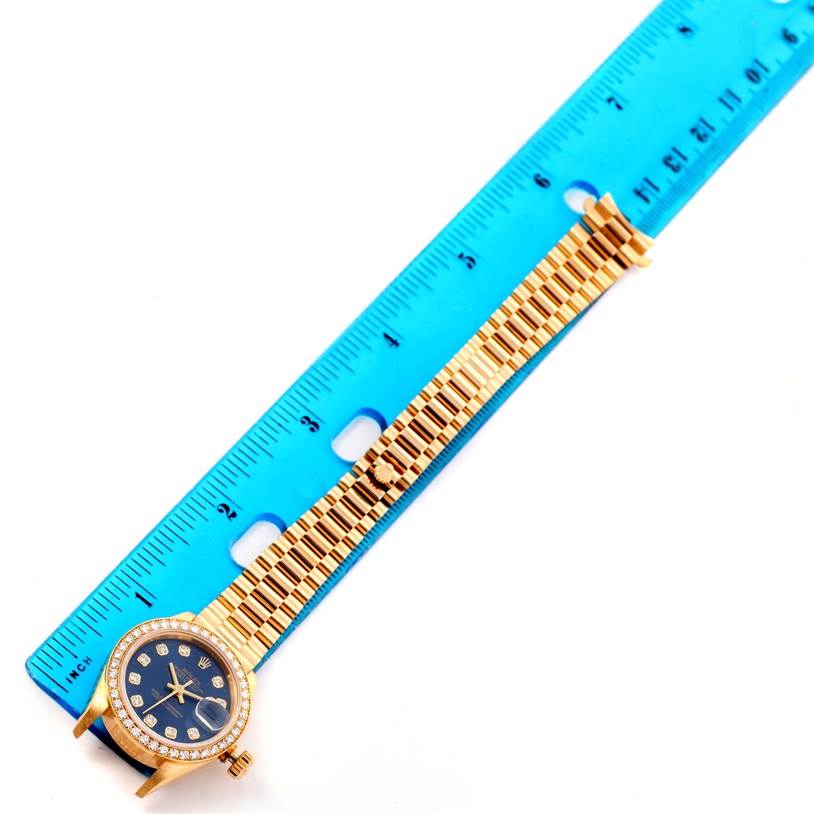The image shows a Rolex President 69138 Women's Yellow Gold Blue Dial 69138 Women's Yellow Gold Blue Dial watch on its side, with the band aligned next to a ruler for measurement.