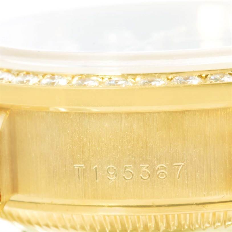 The image shows a close-up of the side of a Rolex President 69138 Women's Yellow Gold Blue Dial 69138 Women's Yellow Gold Blue Dial watch, focusing on the bezel, part of the case, and serial number engraving.