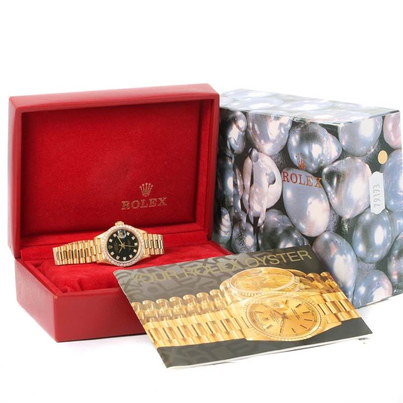 The image shows a Rolex President 69178 Women's Yellow Gold Black Dial 69178 Women's Yellow Gold Black Dial model watch inside its open red box, alongside an outer decorative box and a booklet displaying the watch.