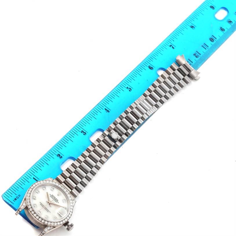 The Rolex President 68159 Women's White Gold Mother of Pearl Dial 68159 Women's White Gold Mother of Pearl Dial watch is shown from an overhead angle with its bracelet laid out beside a ruler.