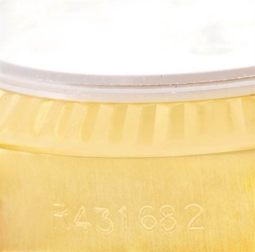 This image shows a close-up of the fluted bezel and engraved serial number on a Rolex President 69178 Women's Yellow Gold White Dial 69178 Women's Yellow Gold White Dial model watch.