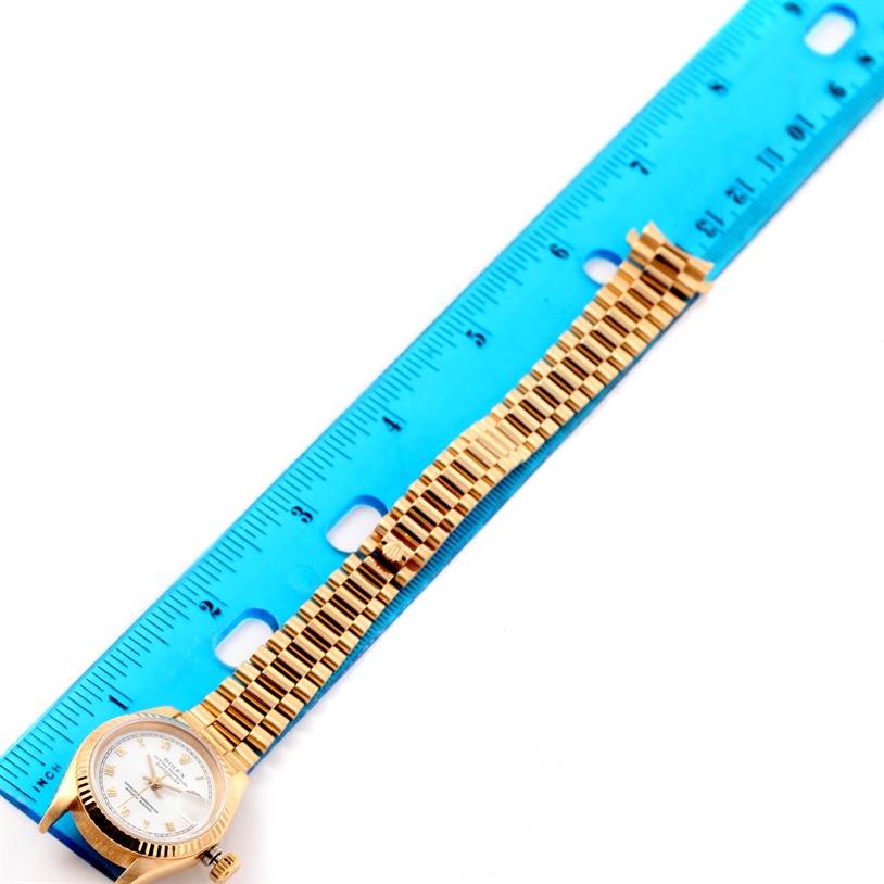 The image shows a Rolex President 69178 Women's Yellow Gold White Dial 69178 Women's Yellow Gold White Dial model watch laid flat next to a blue ruler, displaying the watch face and entire bracelet.