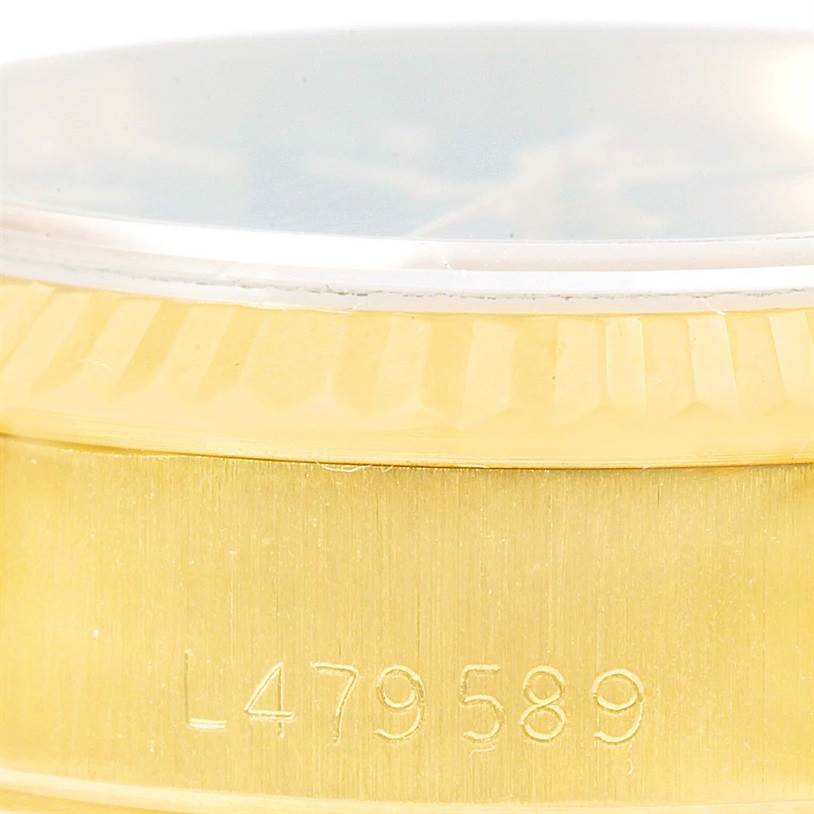 This close-up image of a Rolex President 69178 Women's Yellow Gold Blue Dial 69178 Women's Yellow Gold Blue Dial model watch shows the gold bezel and part of the case with a serial number.