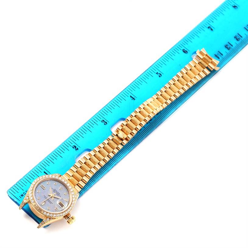The Rolex President 69158 Women's Yellow Gold Mother of Pearl Dial 69158 Women's Yellow Gold Mother of Pearl Dial model watch is shown flat, displaying the face, bezel, and entire bracelet alongside a blue ruler.