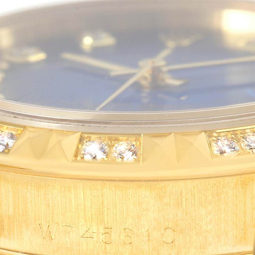 This close-up image of the Rolex President 68258 Women's Yellow Gold Blue Dial 68258 Women's Yellow Gold Blue Dial model showcases the bezel, part of the dial, and part of the engraved watch band.