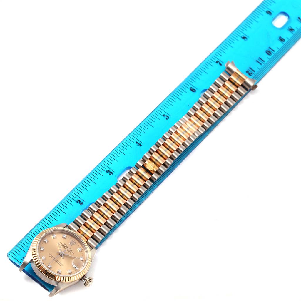 The image shows a Rolex President 68279B Women's White Gold Brown Dial 68279B Women's White Gold Brown Dial model watch lying flat beside a blue ruler, displaying its face, bezel, and bracelet.