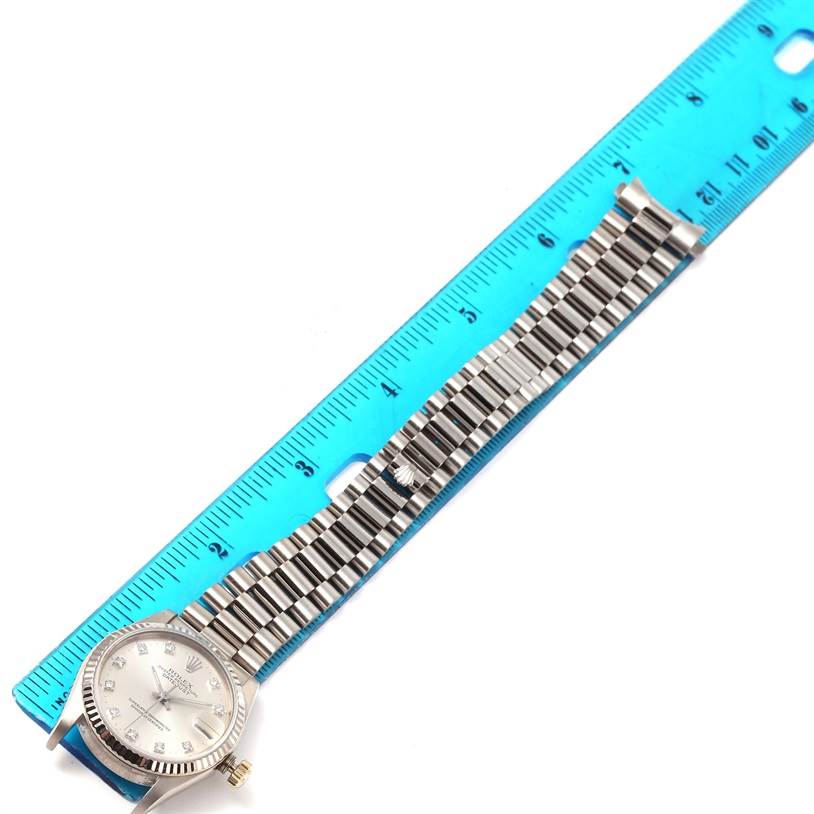 The image shows a Rolex President 68279 Women's White Gold Silver Dial 68279 Women's White Gold Silver Dial model watch placed next to a ruler, highlighting its face, bezel, and bracelet.