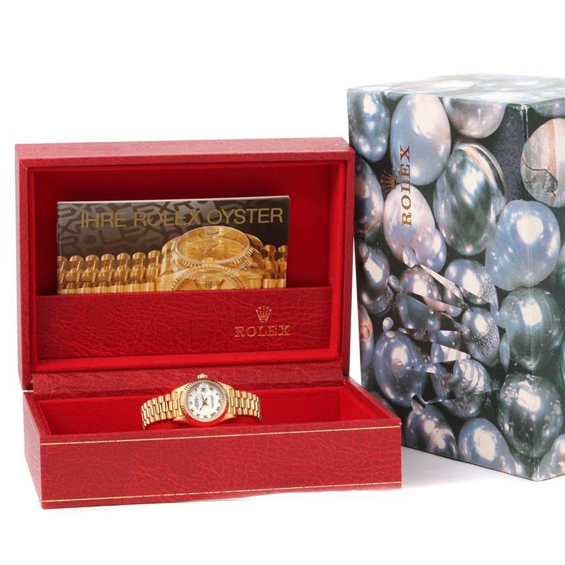 The image shows a Rolex President 69178 Women's Yellow Gold White Dial 69178 Women's Yellow Gold White Dial model watch in an open red box with additional documentation beside a decorative packaging box.
