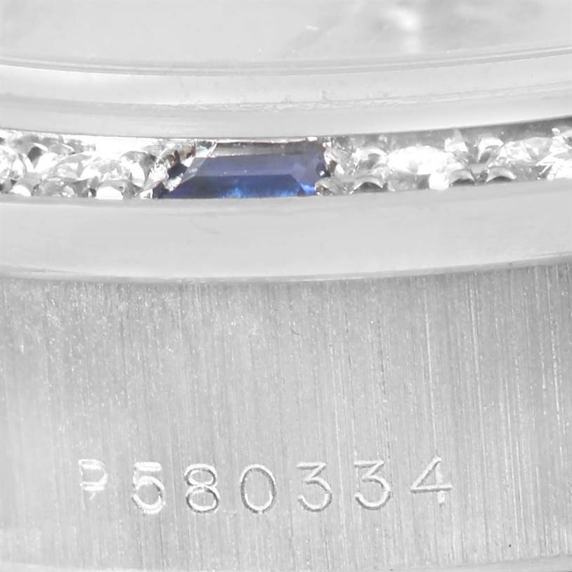 This close-up of the Rolex President 79179 Women's White Gold Silver Dial 79179 Women's White Gold Silver Dial model watch shows a segment of the bezel adorned with gemstones and part of the serial number.