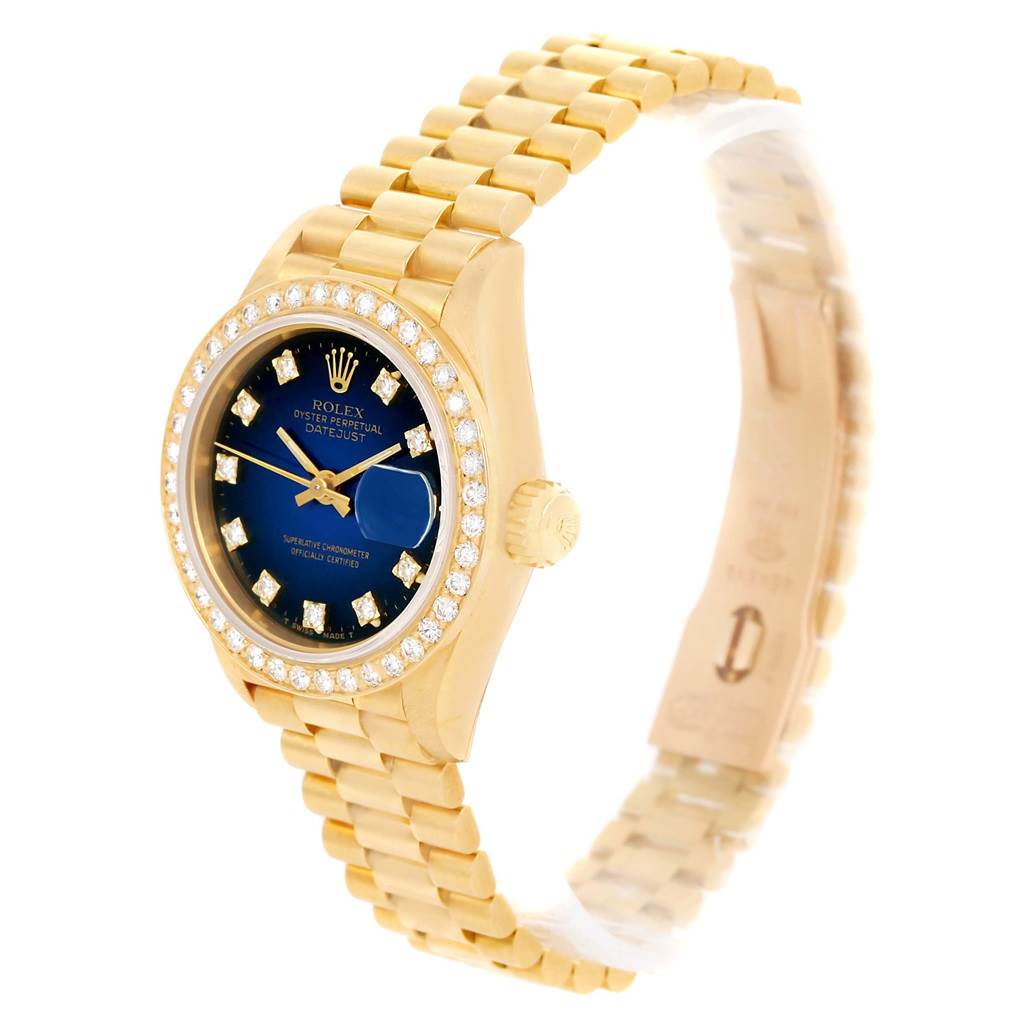 The Rolex President 69138 Women's Yellow Gold Blue Dial 69138 Women's Yellow Gold Blue Dial model watch is shown at an angle highlighting the gold bracelet, blue dial, diamond bezel, and crown.