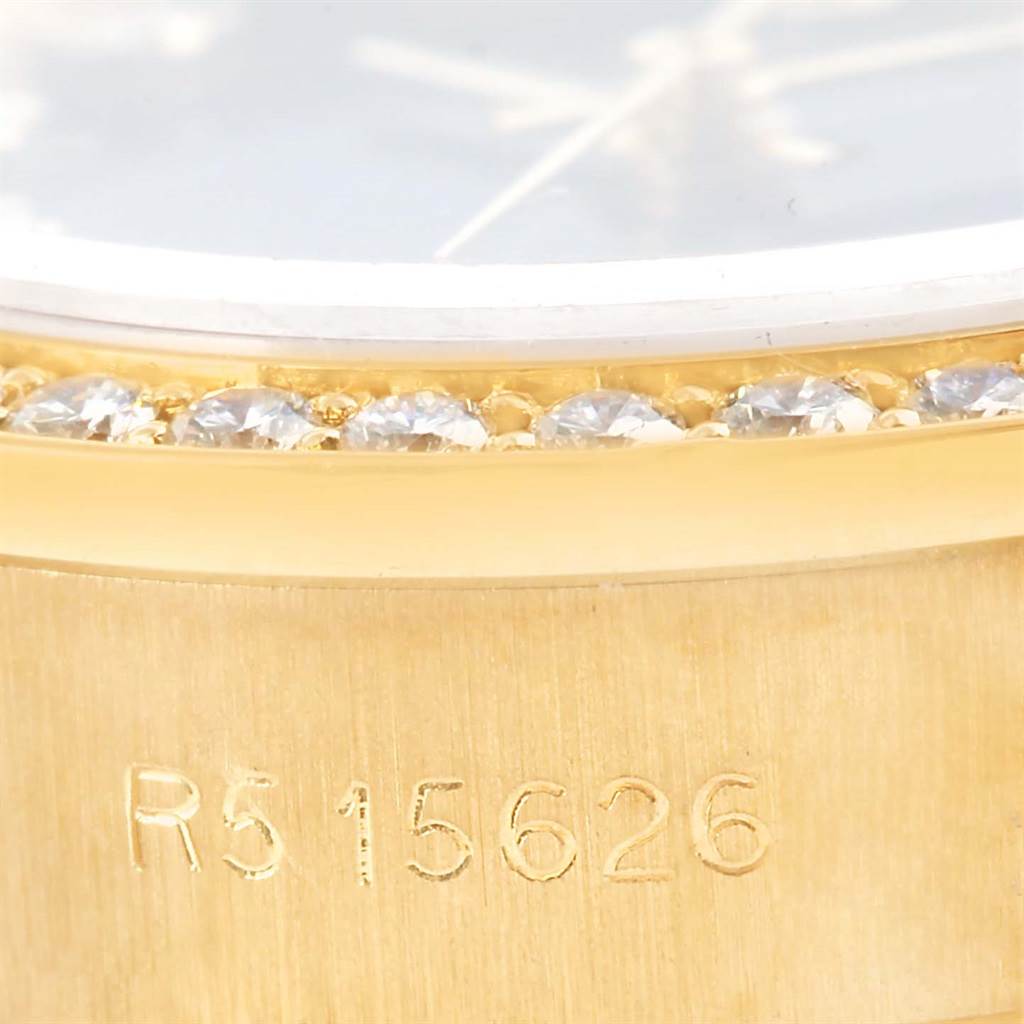 The image shows a close-up of the bezel and serial number on a Rolex President 69138 Women's Yellow Gold Blue Dial 69138 Women's Yellow Gold Blue Dial watch, featuring a diamond-set bezel.