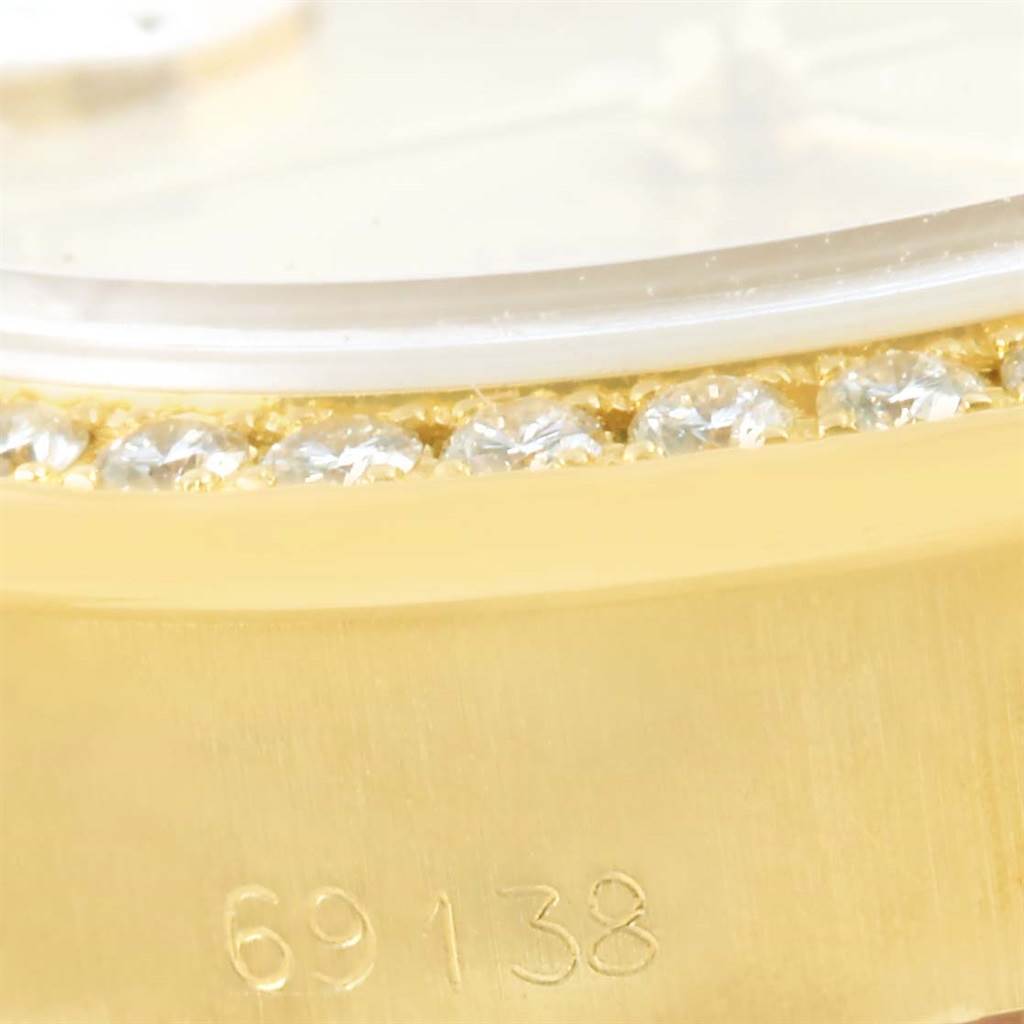 This close-up image of a Rolex President 69138 Women's Yellow Gold Champagne Dial 69138 Women's Yellow Gold Champagne Dial watch shows the bezel with diamonds and the model number 69138 engraved on the case.