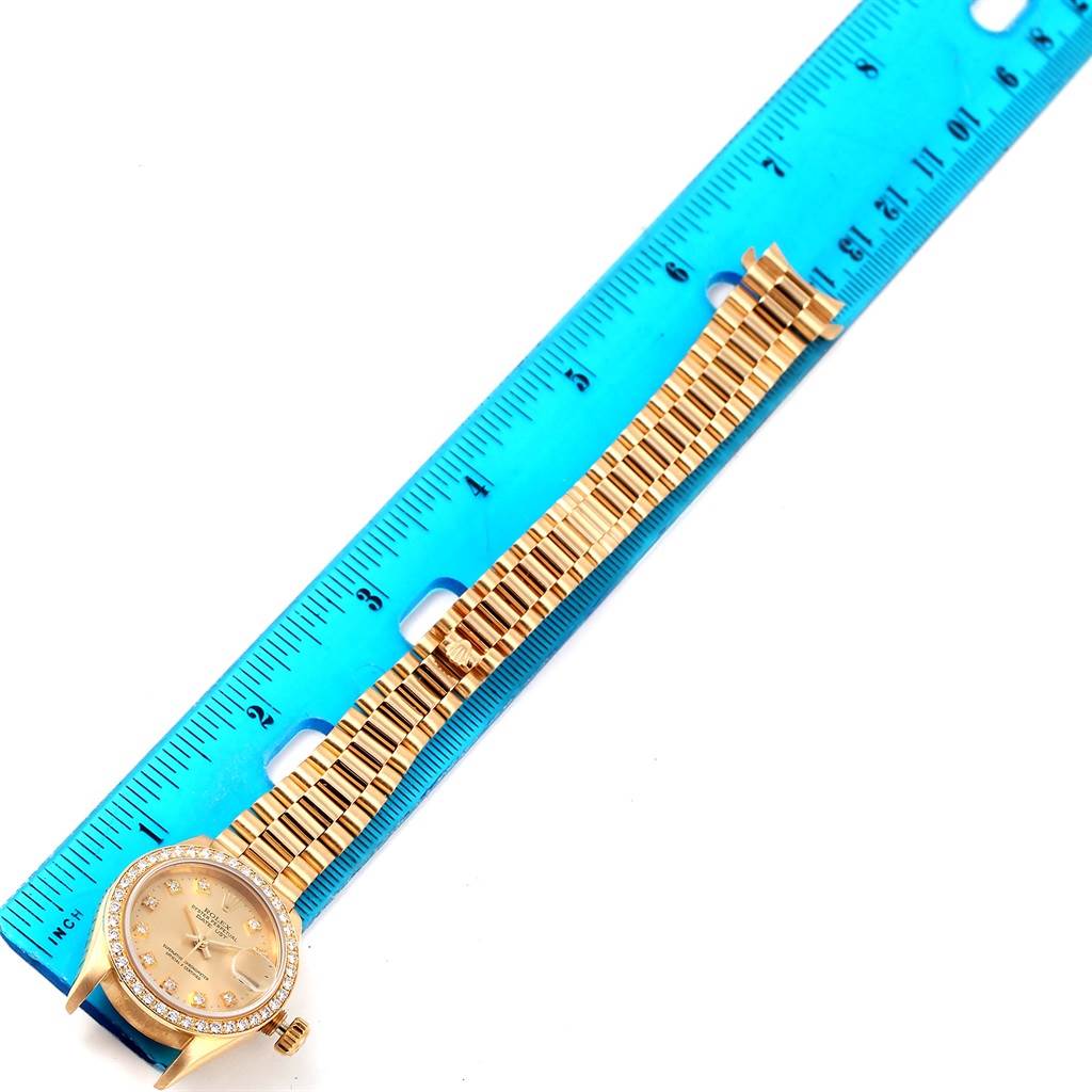 The image shows a top-down view of a Rolex President 69138 Women's Yellow Gold Champagne Dial 69138 Women's Yellow Gold Champagne Dial model watch with a full bracelet and a ruler for measurement.