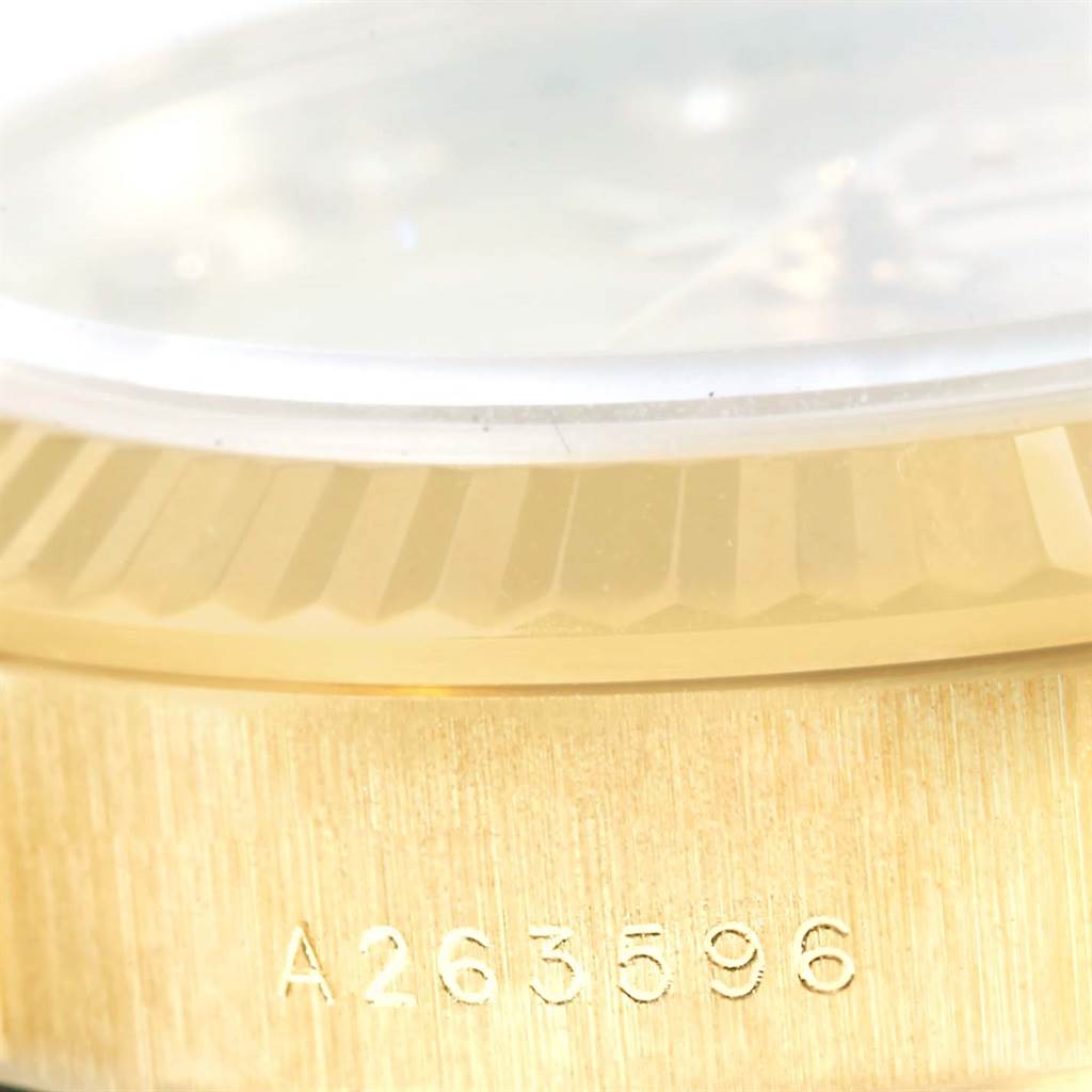 The image shows a close-up of the serial number and the fluted bezel of a Rolex President 76198 Women's Yellow Gold Champagne Dial 76198 Women's Yellow Gold Champagne Dial model watch.