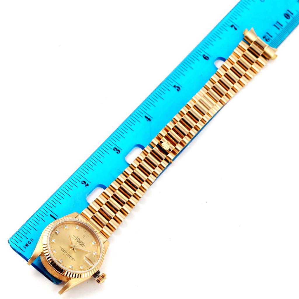 This image shows a Rolex President 68278 Women's Yellow Gold Champagne Dial 68278 Women's Yellow Gold Champagne Dial model watch laid flat with a gold bracelet, next to a blue ruler for scale.