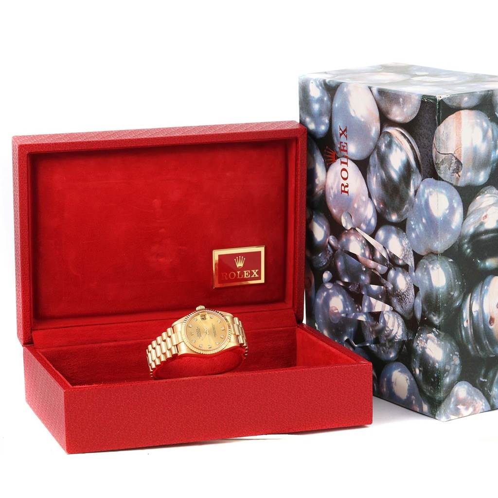 The Rolex President 68278 Women's Yellow Gold Champagne Dial 68278 Women's Yellow Gold Champagne Dial watch is displayed at an angle inside a red box beside its decorative packaging.