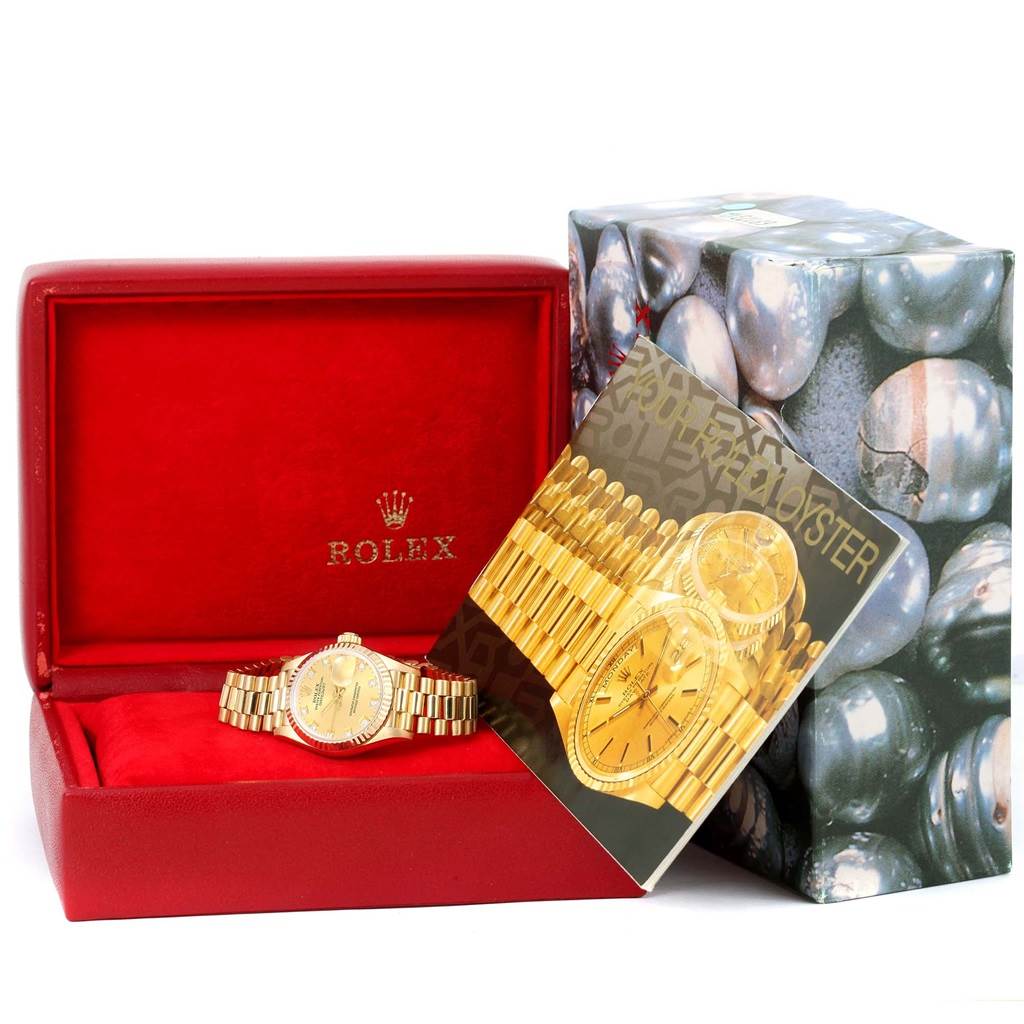 The image shows a Rolex President 69178 Women's Yellow Gold Champagne Dial 69178 Women's Yellow Gold Champagne Dial model watch with its red case and outer packaging from an angled front view.