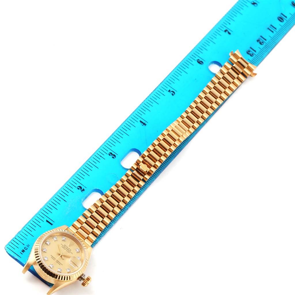 The image shows a Rolex President 69178 Women's Yellow Gold Champagne Dial 69178 Women's Yellow Gold Champagne Dial model watch positioned diagonally, with a ruler measuring its band length.