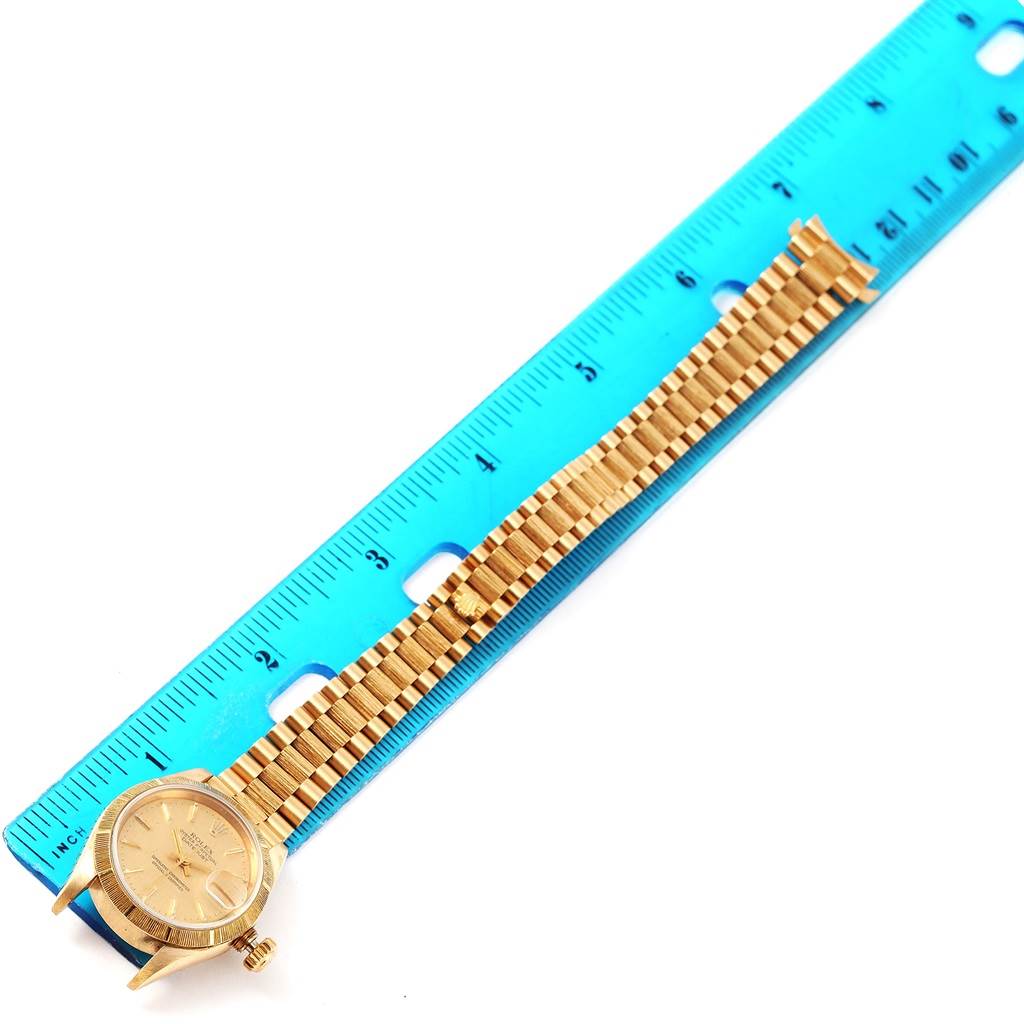 The image shows a Rolex President 69278 Women's Yellow Gold Champagne Dial 69278 Women's Yellow Gold Champagne Dial watch placed alongside a blue ruler, displaying its full length and gold bracelet.