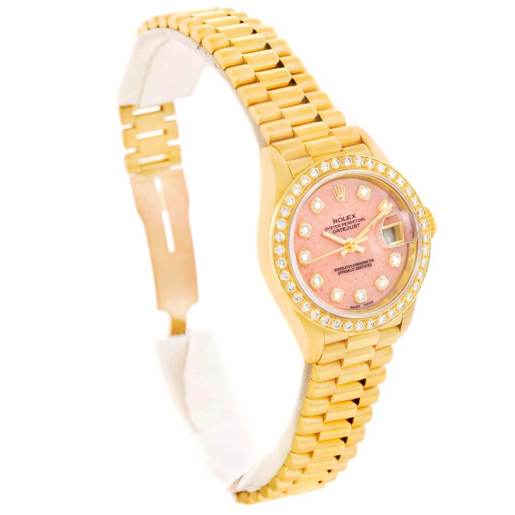 The image shows a Rolex President 69138 Women's Yellow Gold Pink Dial 69138 Women's Yellow Gold Pink Dial model watch at a three-quarter angle, highlighting its pink dial, gold bracelet, and diamond-encrusted bezel.