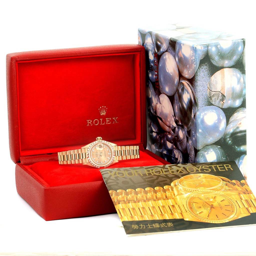 The image shows the Rolex President 69158 Women's Yellow Gold Champagne Dial 69158 Women's Yellow Gold Champagne Dial model watch inside its red box, accompanied by a booklet and an outer box with a pearl design.