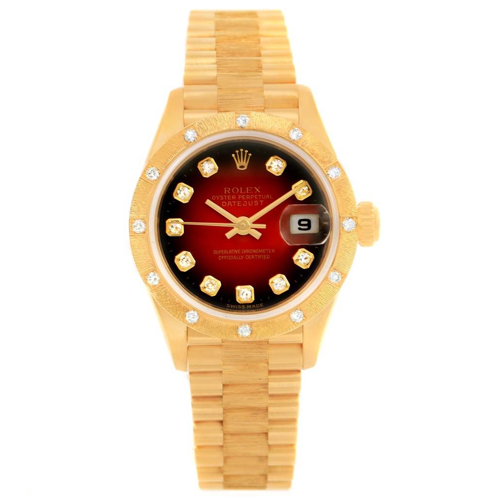 The image shows a front view of a Rolex President 79288 Women's Yellow Gold Red Dial 79288 Women's Yellow Gold Red Dial model watch, featuring a gold bracelet, a diamond-encrusted bezel, and a date window.