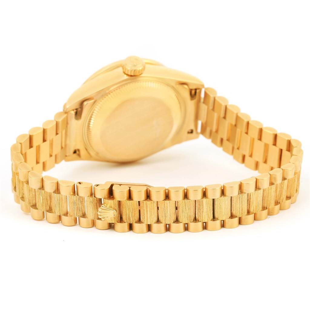 The image shows the back of a Rolex President 79288 Women's Yellow Gold Red Dial 79288 Women's Yellow Gold Red Dial model watch, highlighting the case back and the President bracelet with a clasp.