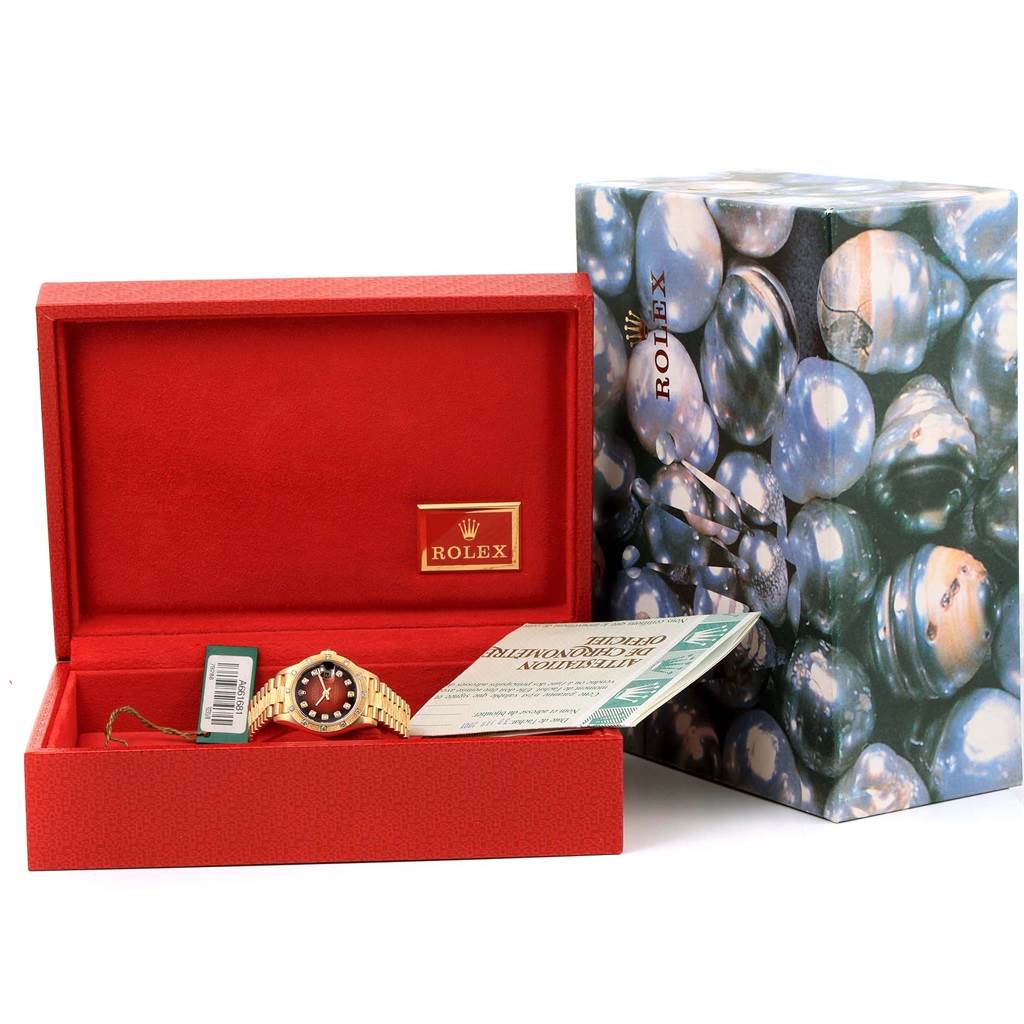 The image shows the Rolex President 79288 Women's Yellow Gold Red Dial 79288 Women's Yellow Gold Red Dial model watch in its open box, accompanied by a certificate and a branded outer box.