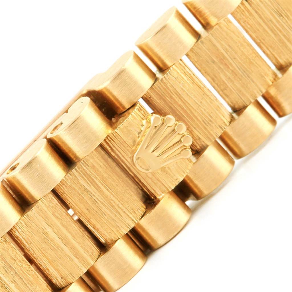 This image shows a close-up angle of the bracelet of a Rolex President 79288 Women's Yellow Gold Red Dial 79288 Women's Yellow Gold Red Dial model watch, featuring the iconic Rolex crown logo.