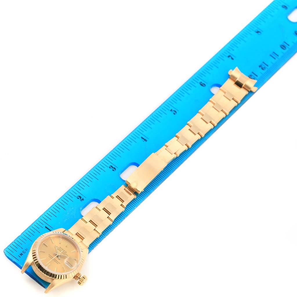 The image shows a Rolex President 69178 Women's Yellow Gold Champagne Dial 69178 Women's Yellow Gold Champagne Dial watch laid flat next to a blue ruler, displaying the watch band and face.