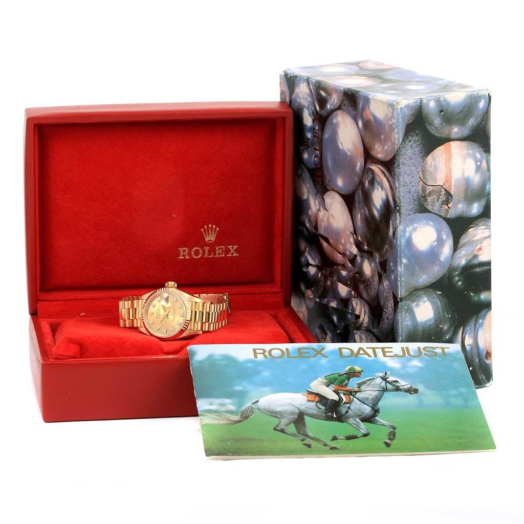 The image shows a Rolex President 69178 Women
s Yellow Gold Champagne Dial 69178 Women
s Yellow Gold Champagne Dial model watch inside its box along with a Rolex Datejust booklet and the watch
s outer packaging.