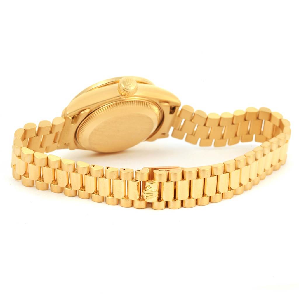The image shows the back of a Rolex President 69138 Women
s Yellow Gold White Dial 69138 Women
s Yellow Gold White Dial model watch, highlighting its gold case and bracelet.